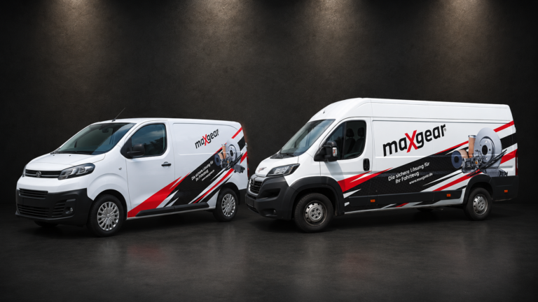 Dwa białe samochody dostawcze Maxgear z czerwono-czarnym oklejeniem i grafiką części motoryzacyjnych