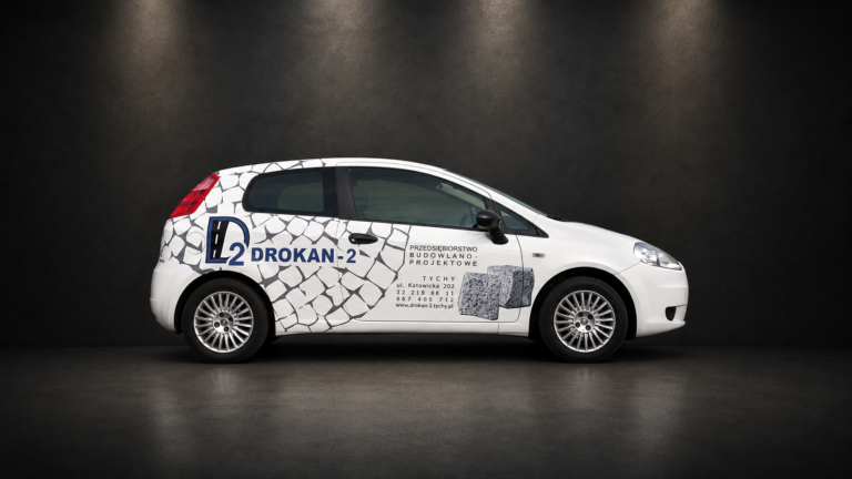 Biały samochód osobowy Drokan-2 z grafiką kostki brukowej, logo i danymi kontaktowymi